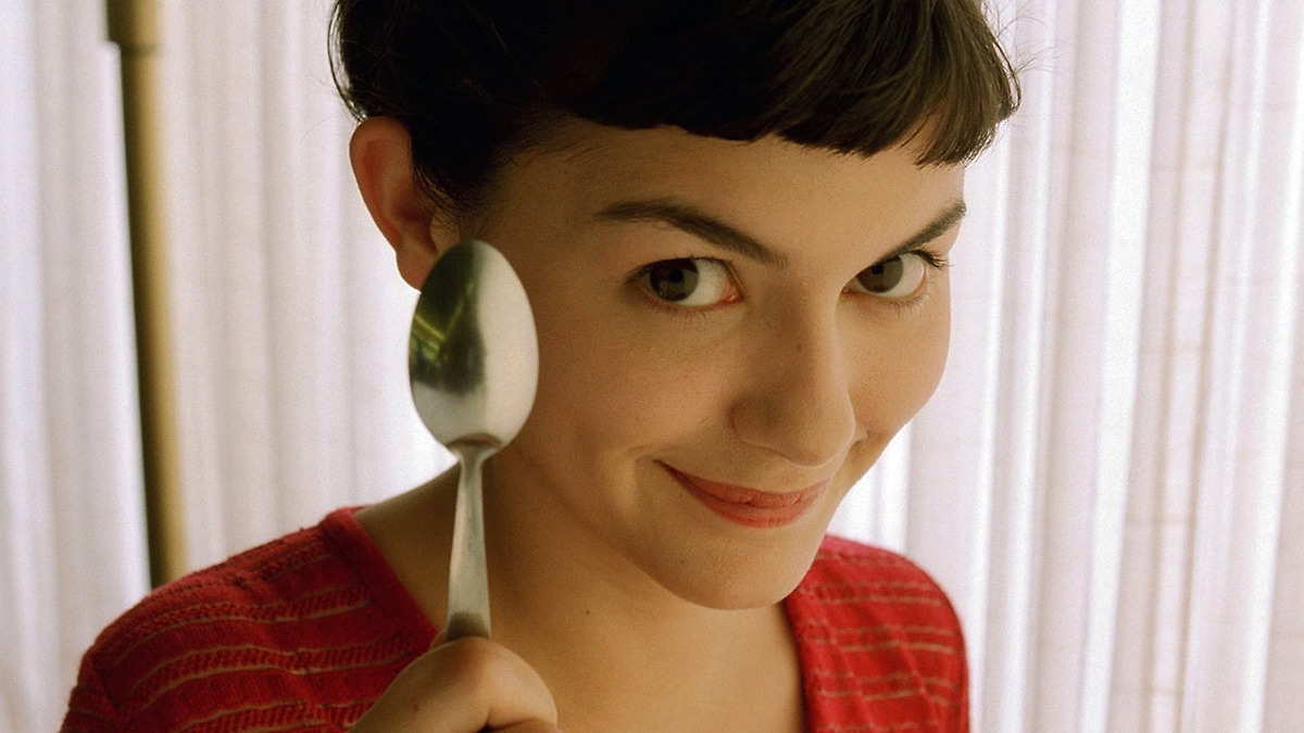 A lady smiling and holding a silver spoon.