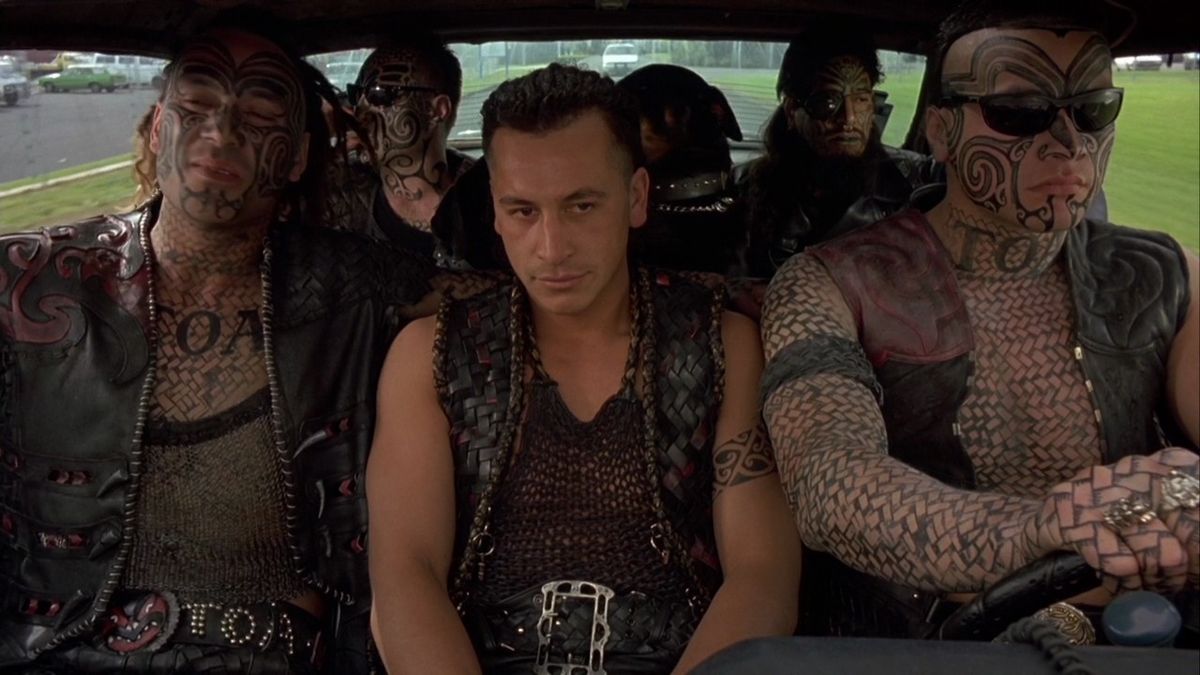 A vehicle with five tattooed men and a black dog.