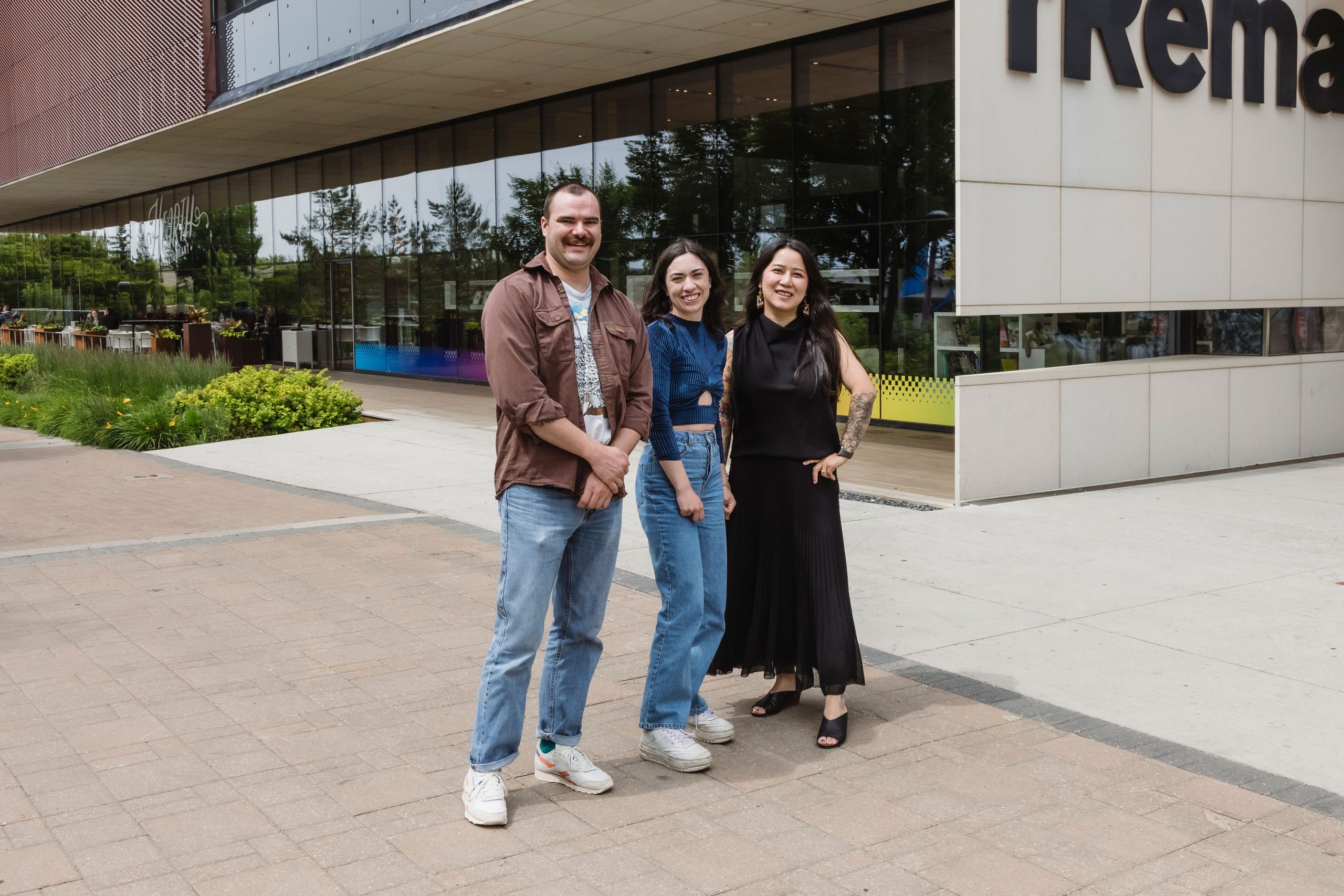 The three artists selected for the RBC Sustained Artist Mentorship program for 2024-25, Luke Maddaford, Gabby Da Silva and Xiao Han, stand outside of Remai Modern.