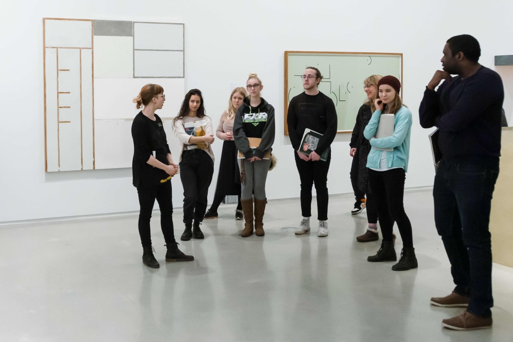 A photo of a group of people in a tour of a gallery.