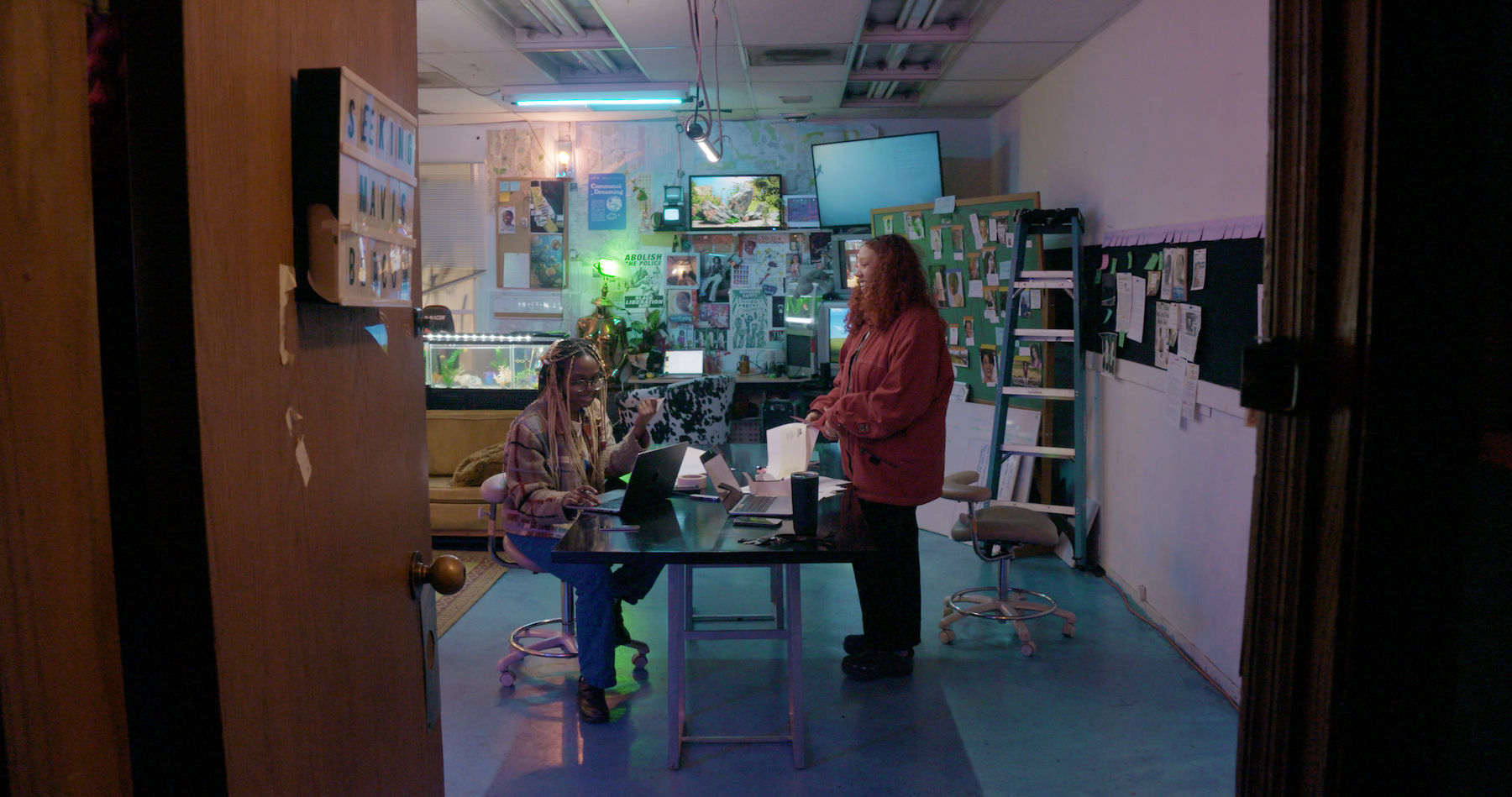 In a comfortable room, two women are gathered around a table, sharing a moment of laughter and conversation.