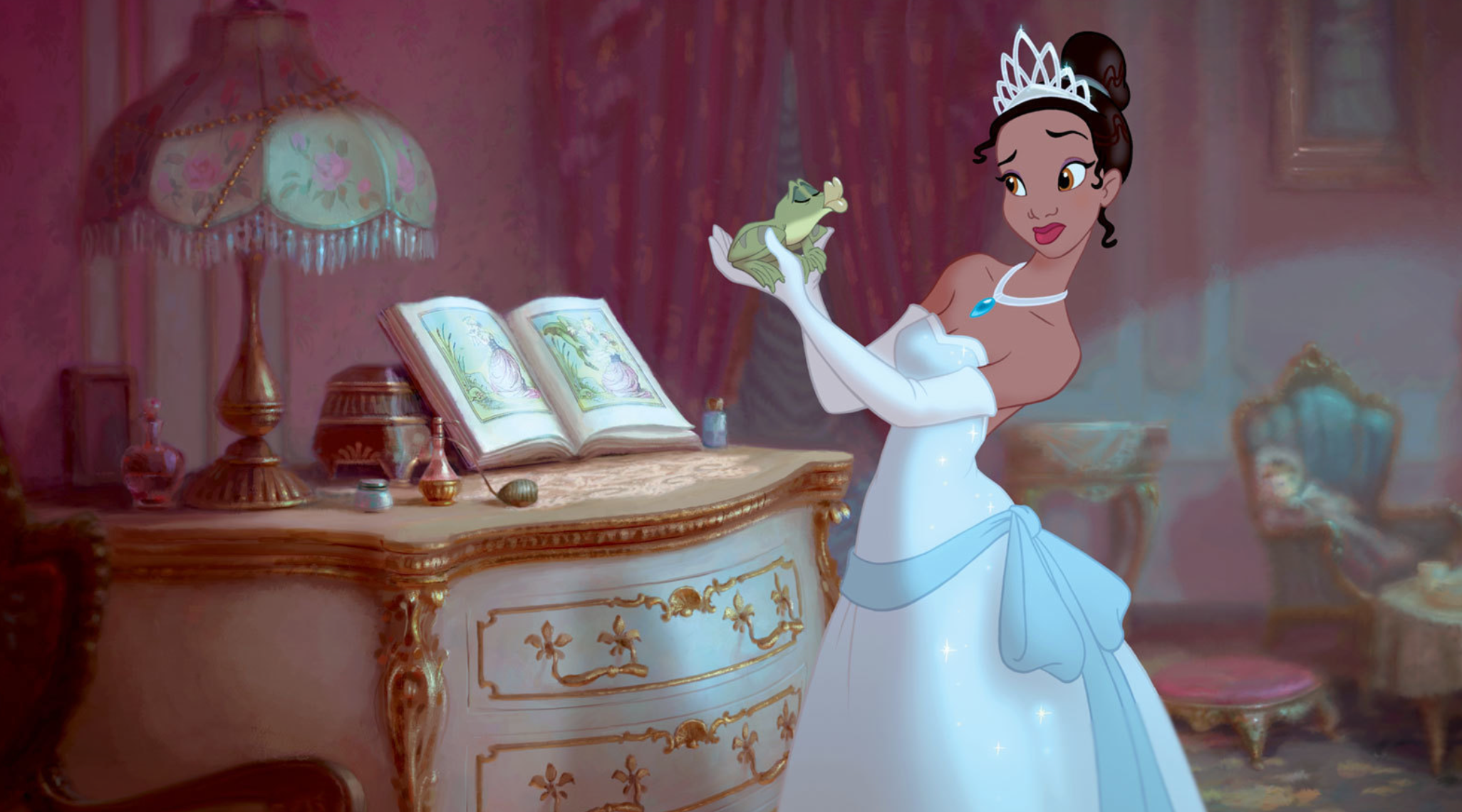 An animated princess in a white ball gown and tiara stands in an elegant bedroom, holding a small green frog in her gloved hands and looking at it with surprise and uncertainty. A decorative dresser with an open storybook, perfume bottles, and a fringed lamp sits behind her.