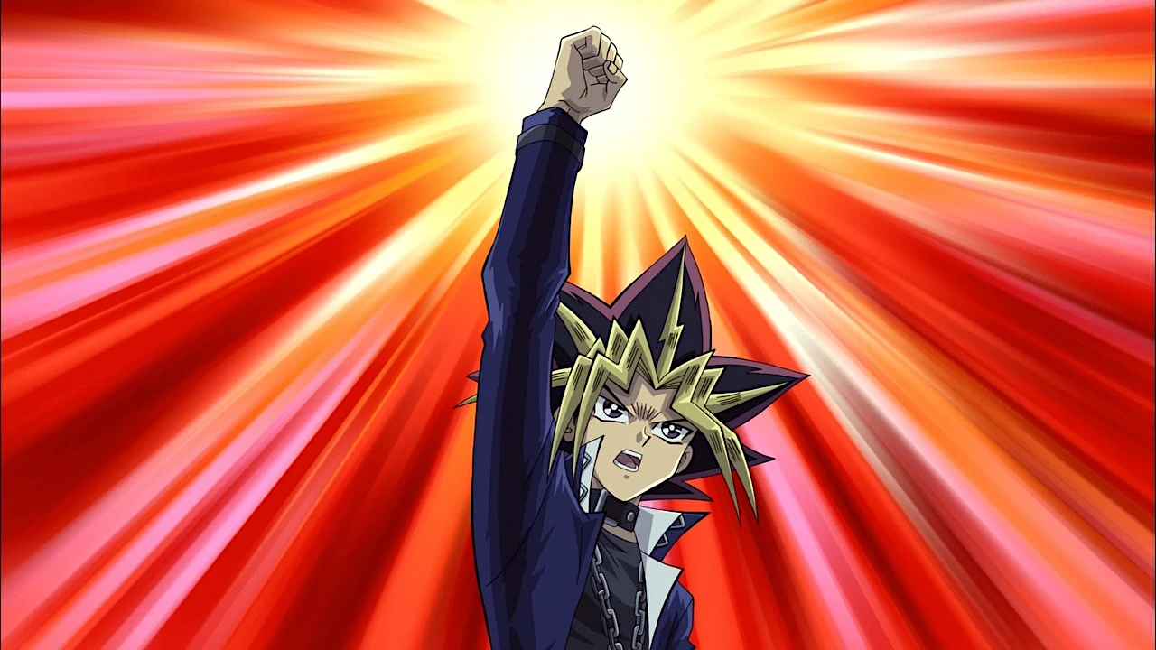 yugioh An anime character with dramatic spiky black and gold hair thrusts a fist triumphantly into the air against a blazing red and yellow radial burst background. The character wears a dark jacket with a white collar and has an intense, determined expression, depicted in a classic early 2000s anime style.